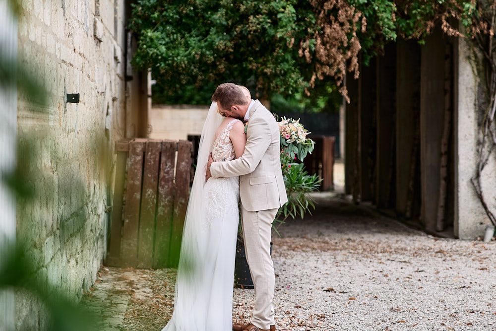 Harmonie et Anthony s’embrassent dans un passage en pierre du Domaine des Pommerieux